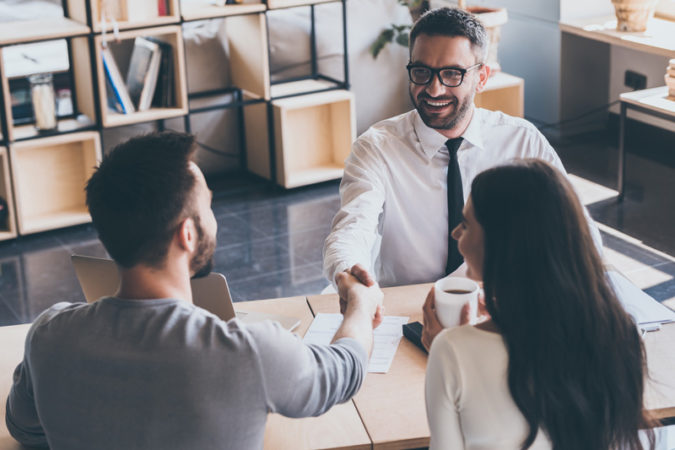 Man in suit shaking hands of clients